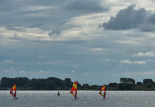 Windsurfer sull'acqua presso il campeggio de Haas a Zeeland, Paesi Bassi, sotto un cielo nuvoloso.