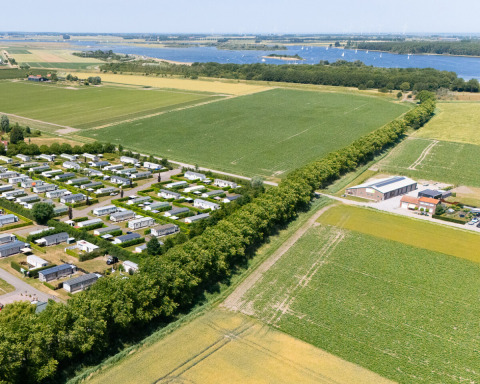 Vista aerea del campeggio de Haas in Zelanda, Paesi Bassi, con case vacanza, campi agricoli e un fiume.