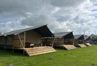 Safari tents with wooden decks at Mini Campsite Marina Warns in the Netherlands under a cloudy sky.