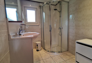 Modern bathroom with shower cabin, sink, and window inside the Comfort cabin at De Woudhoeve, Netherlands.