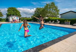 Two children jump into an outdoor pool at a Comfort cabin complex in De Woudhoeve, Netherlands.