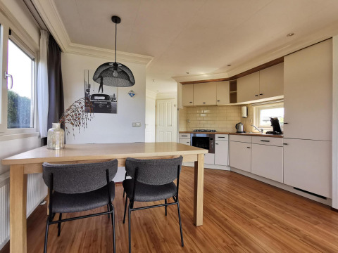 Modern kitchen and dining area in the Comfort cabin at De Woudhoeve, Netherlands, featuring wood flooring.