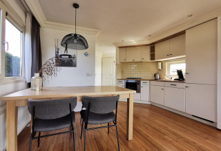 Modern kitchen and dining area in the Comfort cabin at De Woudhoeve, Netherlands, featuring wood flooring.