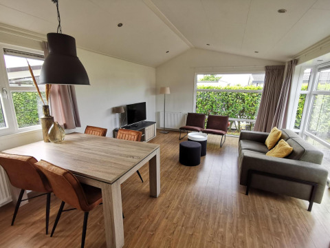 Living room in a Comfort cabin at De Woudhoeve, Netherlands, featuring modern decor and large windows.