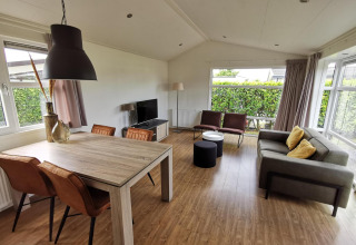 Living room in a Comfort cabin at De Woudhoeve, Netherlands, featuring modern decor and large windows.