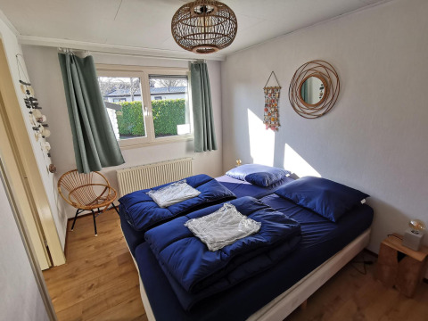 Bedroom in Comfort cabin at De Woudhoeve, Netherlands, featuring blue bedding and modern decor.