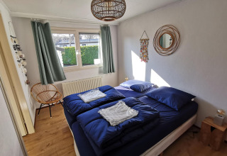 Bedroom in Comfort cabin at De Woudhoeve, Netherlands, featuring blue bedding and modern decor.