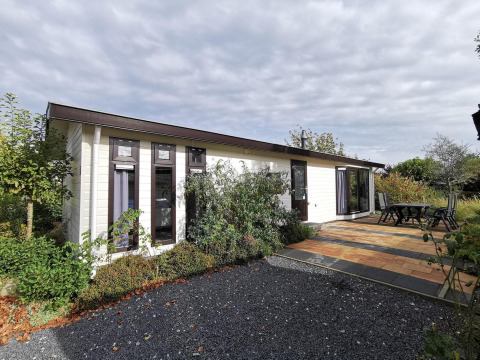 Exterior view of Comfort cabin at De Woudhoeve in the Netherlands, with a patio, garden, and outdoor seating.