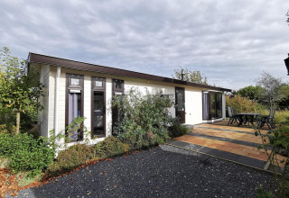 Exterior view of Comfort cabin at De Woudhoeve in the Netherlands, with a patio, garden, and outdoor seating.