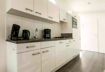 Moderne keuken in een Comfort-cabine bij De Woudhoeve, Nederland, met witte kasten en apparaten.
