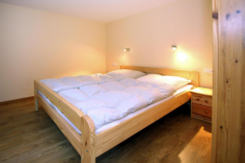 Slaapkamer in Bungalow «35 qm 2 Pers» in Duitsland, met houten meubilair en warme verlichting.