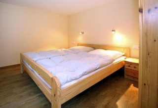 Slaapkamer in Bungalow «35 qm 2 Pers» in Duitsland, met houten meubilair en warme verlichting.