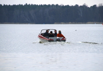 Cuatro personas en lancha motora en un lago junto al Holiday home «Susanne 58 qm» en Alemania.