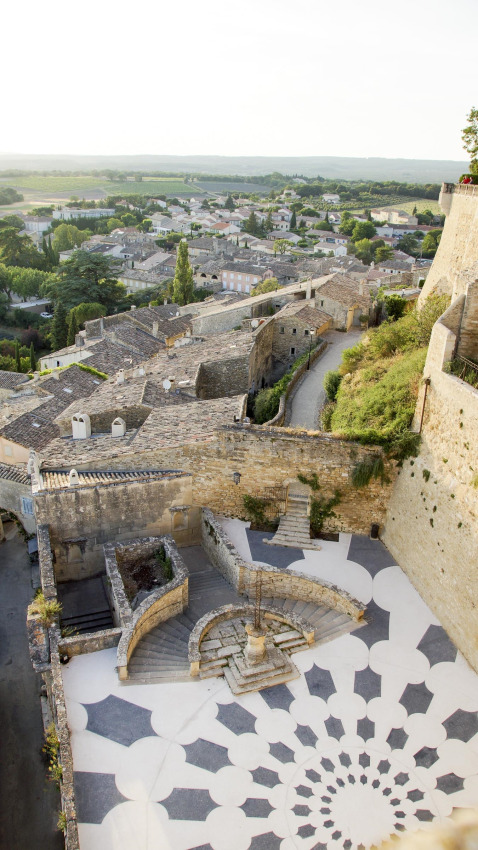 View of a patterned courtyard and old town from Flower Camping la Pinède in Auvergne-Rhône-Alpes, France.