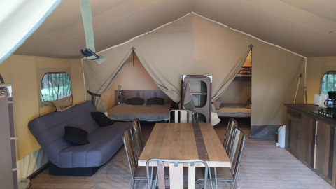 Interieur van Raised Lodge Comfort 46m² safaritent op Flower Camping La Rivière in Frankrijk, met meubels en bedden.