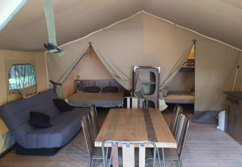 Innenansicht des Raised Lodge Comfort 46m² Safarizeltes bei Flower Camping La Rivière in Frankreich mit Möbeln.