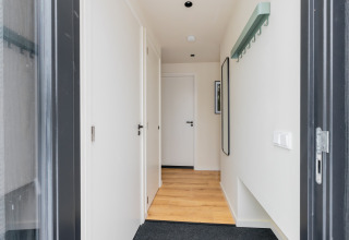 Ingresso della Forest villa «De Bosburcht» con pavimento in legno chiaro, porte bianche e stile minimalista.