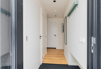 Hallway at Forest villa «De Bosburcht» with light wood flooring, white doors, and minimalist decor.