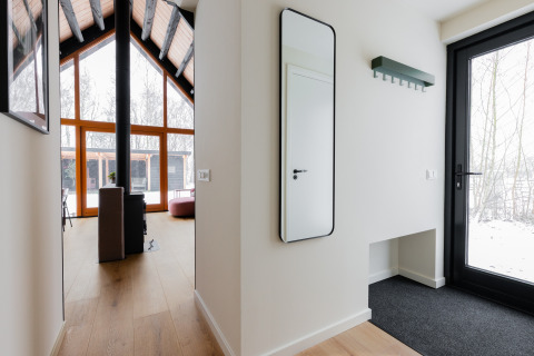 Lichte inkomhal in Forest villa «De Bosburcht» bij De Kremmer, Nederland, met spiegel en grote ramen.