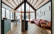 Moderne hytte med højt loft, store vinduer, træindretning og udsigt over snedækket skov ved De Kremmer.