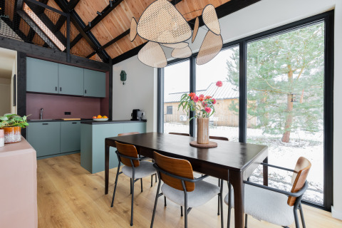 Zona pranzo moderna con cucina in legno e ampie finestre, vista sugli alberi innevati a Forest villa De Bosburcht.