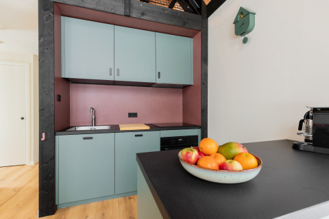 Cucina moderna nella Forest villa «De Bosburcht» a De Kremmer, con mobili pastello e ciotola di frutta.