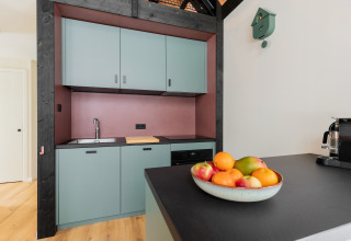 Cucina moderna nella Forest villa «De Bosburcht» a De Kremmer, con mobili pastello e ciotola di frutta.