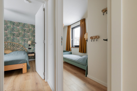 Vista dal corridoio su due camere da letto alla Forest villa «De Bosburcht» con carta da parati forestale.