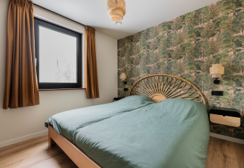 Slaapkamer in Forest villa «De Bosburcht» te De Kremmer, Nederland, met bosbehang en groen beddengoed.