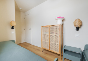 Lichte slaapkamer in Forest villa «De Bosburcht» met rotan kast en nachtkastje, Nederland.
