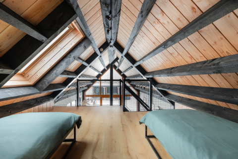 Zolderkamer met twee bedden, houten plafond en donkere balken in Forest villa «De Bosburcht», De Kremmer, Nederland.