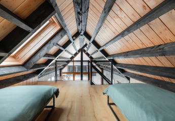 Loftsoveværelse med to senge, træpaneler og sorte bjælker i Forest villa «De Bosburcht», De Kremmer, Holland.