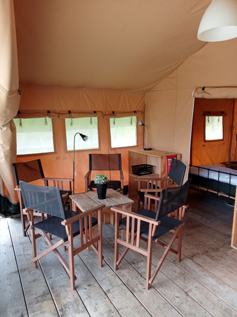 Innenaufnahme eines Safari-Zeltes auf dem Campingplatz La Perle in Frankreich mit Stühlen und Tisch.