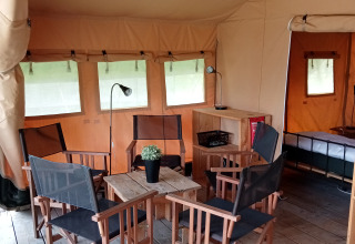 Innenaufnahme eines Safari-Zeltes auf dem Campingplatz La Perle in Frankreich mit Stühlen und Tisch.