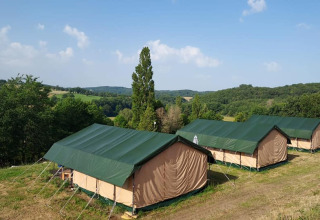 Tentes safari au Camping La Perle en France, installées sur une colline verdoyante avec une vue sur la campagne.