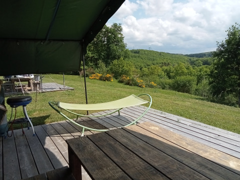 Blick von einer Safari-Zeltterrasse auf dem Campingplatz La Perle in Frankreich mit grüner Landschaft.