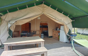 Safari-Zelt auf dem Campingplatz La Perle in Frankreich mit Holzbank, Hängematte und Innenküche.