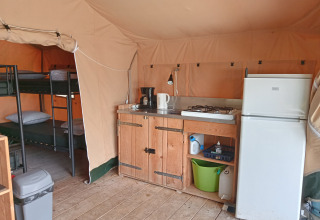 Innenansicht eines Safari-Zeltes auf Campingplatz La Perle in Frankreich mit Küche und Etagenbetten.
