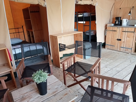Innenansicht eines Safari-Zeltes auf dem Campingplatz La Perle in Frankreich mit Betten und Sitzbereich.