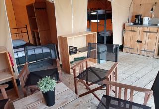Innenansicht eines Safari-Zeltes auf dem Campingplatz La Perle in Frankreich mit Betten und Sitzbereich.