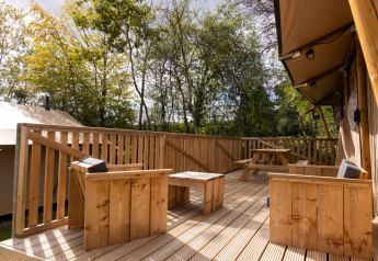 Terrasse en bois avec fauteuils et table de pique-nique au Stardust 40 Family Lodge, Arden Parks, France.