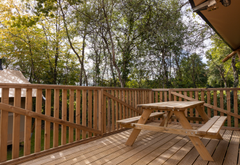 Terrasse en bois avec banc pique-nique, vue sur la forêt au Stardust 40 Family Lodge, Arden Parks, France.