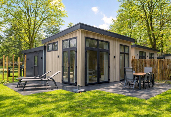 Lodge Veldzicht lumineux avec terrasse moderne, chaises longues et coin repas extérieur sous les arbres.