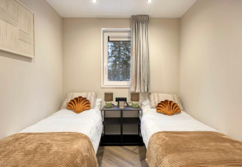 Deux lits simples avec des coussins dorés dans une chambre du pavillon Veldzicht, Forest Park Ede, Pays-Bas.