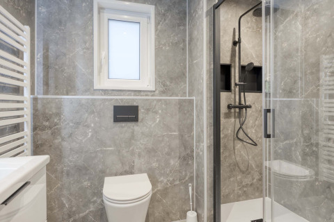 Baño moderno con baldosas de mármol, cabina de ducha, inodoro y ventana en Veldzicht, Forest Park Ede.