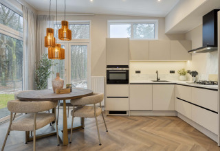 Cuisine moderne et coin repas au lodge « Veldzicht » à Forest Park Ede, Pays-Bas, avec grandes fenêtres et éclairage sophistiqué.
