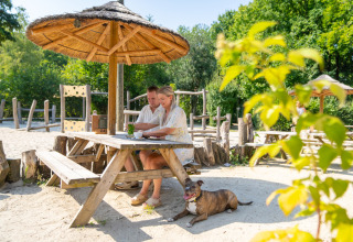 Par på ferie ved et træbord med hund på Gooise Heide i Nordholland, Nederlandene om sommeren.