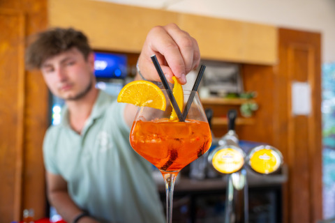 Bartender at Gooise Heide holiday park in North-Holland serving Aperol Spritz with orange garnish.