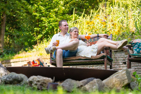 Et afslappet par nyder drinks udenfor på en bænk, omgivet af grøn natur på Gooise Heide, Holland.