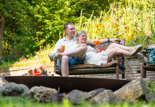 Et afslappet par nyder drinks udenfor på en bænk, omgivet af grøn natur på Gooise Heide, Holland.